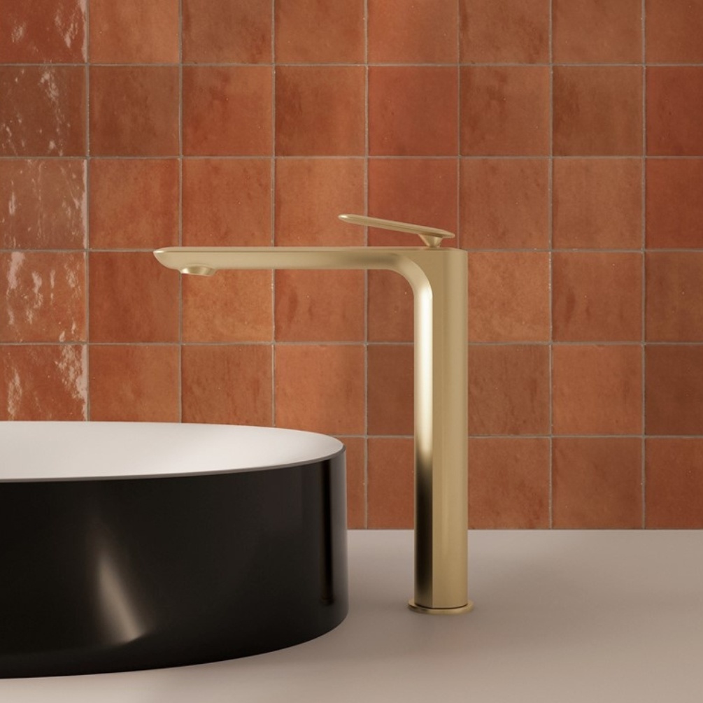 Lifestyle image of the Crosswater Huck Brushed Brass Tall Basin Mixer installed to the side of a black and white round countertop basin